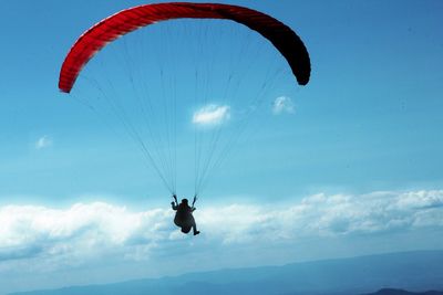 Low angle view of person paragliding against blue sky