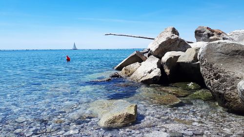 Rocks in sea against blue sky