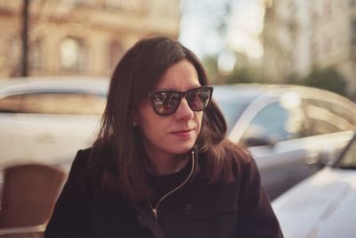 Beautiful woman wearing sunglasses standing against car