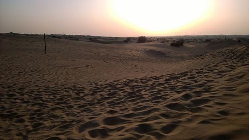 Scenic view of sand dune on beach against sky during sunset