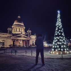 Man pointing at christmas tree outside st isaac cathedral at night