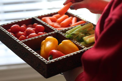 Midsection of woman holding container with various vegetables