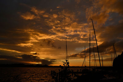 Silhouette sailboats on sea against dramatic sky during sunset