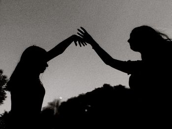 Silhouette couple kissing against sky