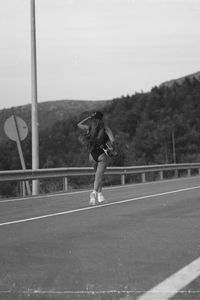 Rear view of woman standing on road against sky