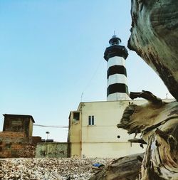 Low angle view of lighthouse amidst buildings against clear sky