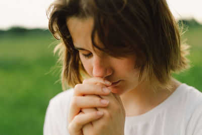 Teenager girl closed her eyes, praying. hands folded in prayer concept for faith