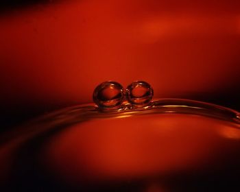 Close-up of water drop on table against red background