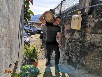 Smiling man carrying log on shoulder at footpath