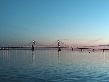 Bridge over calm sea against clear sky