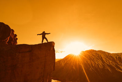 Silhouette man standing on rock