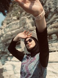 Midsection of woman holding sunglasses while standing on land