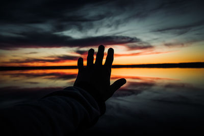 Midsection of person against sea during sunset