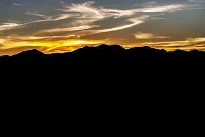 Scenic view of dramatic sky over silhouette mountains