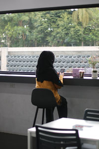 Rear view of woman sitting on table