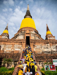 People outside temple against building and sky