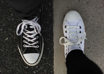 Low section of friends wearing canvas shoes on road