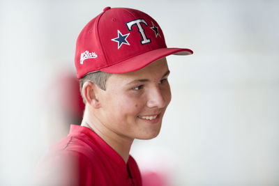 Close-up portrait of teen baseball player in red cap and uniform