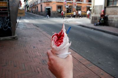 Cropped hand of man holding ice cream on road