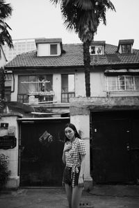 Portrait of woman standing against house in city