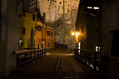 Walkway amidst illuminated buildings in city at night