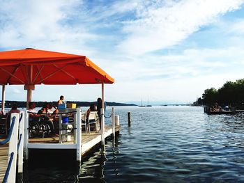 People in gazebo over sea against sky