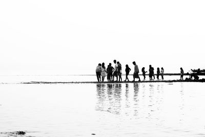 People on beach against clear sky