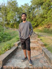 Portrait of young man standing on footpath