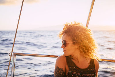 Portrait of young woman looking at sea against sky