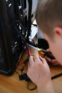 A man repairs a cable in a system unit and connects electrical wires