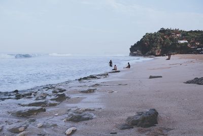 People enjoying at beach against sky