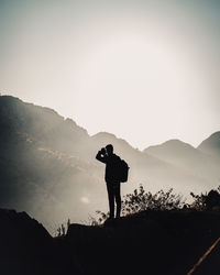 Silhouette in man photographing while standing on mountain against sky