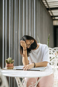 Young woman using mobile phone while sitting on table