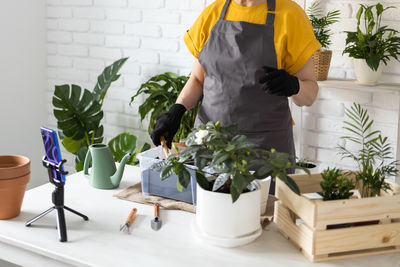 Midsection of woman holding potted plant on table