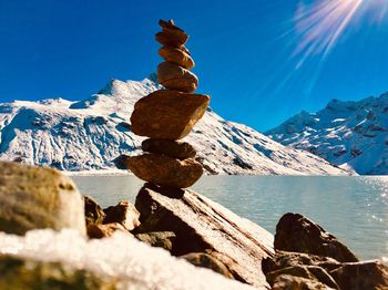 Scenic view of sea by snowcapped mountains against blue sky