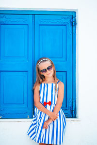 Woman wearing sunglasses standing against blue door