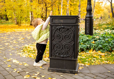 Full length of boy standing on footpath during autumn