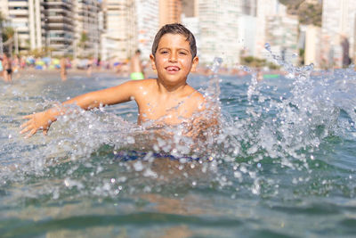 Funny kid spalshing water on an urban beach