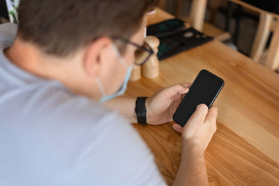 Man using mobile phone on table in cafe