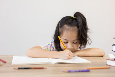 Close-up of young woman writing in book at home