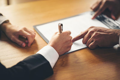 Close-up of man holding hands on table