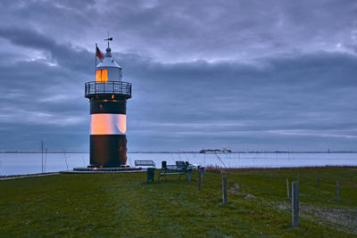 Lighthouse by sea against sky