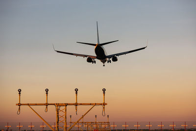 Low angle view of airplane flying against sky during sunset