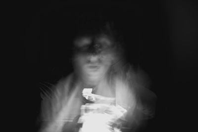 Close-up of young woman against black background