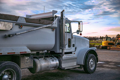 Construction truck. gray commercial construction truck in foreground. excavator is in background.