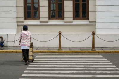 Rear view of man walking on zebra crossing