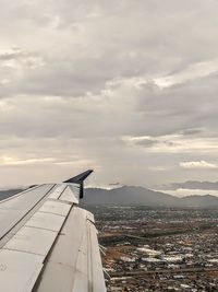 Airplane flying over city against sky