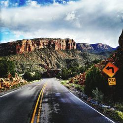 Directional sign by empty road leading towards colorado national monument