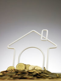 Close-up of coins and model home against gray background