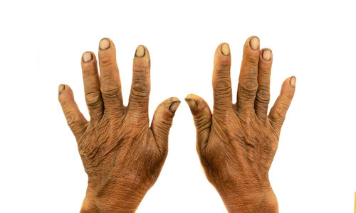 Close-up of wrinkled human hands against white background